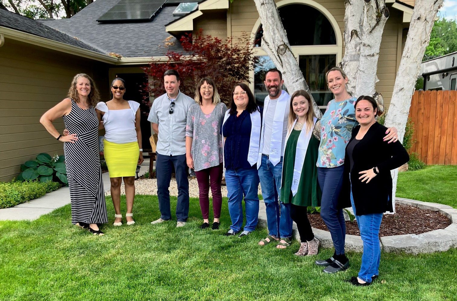 A group of people posing for a photo outside in front of a tree.